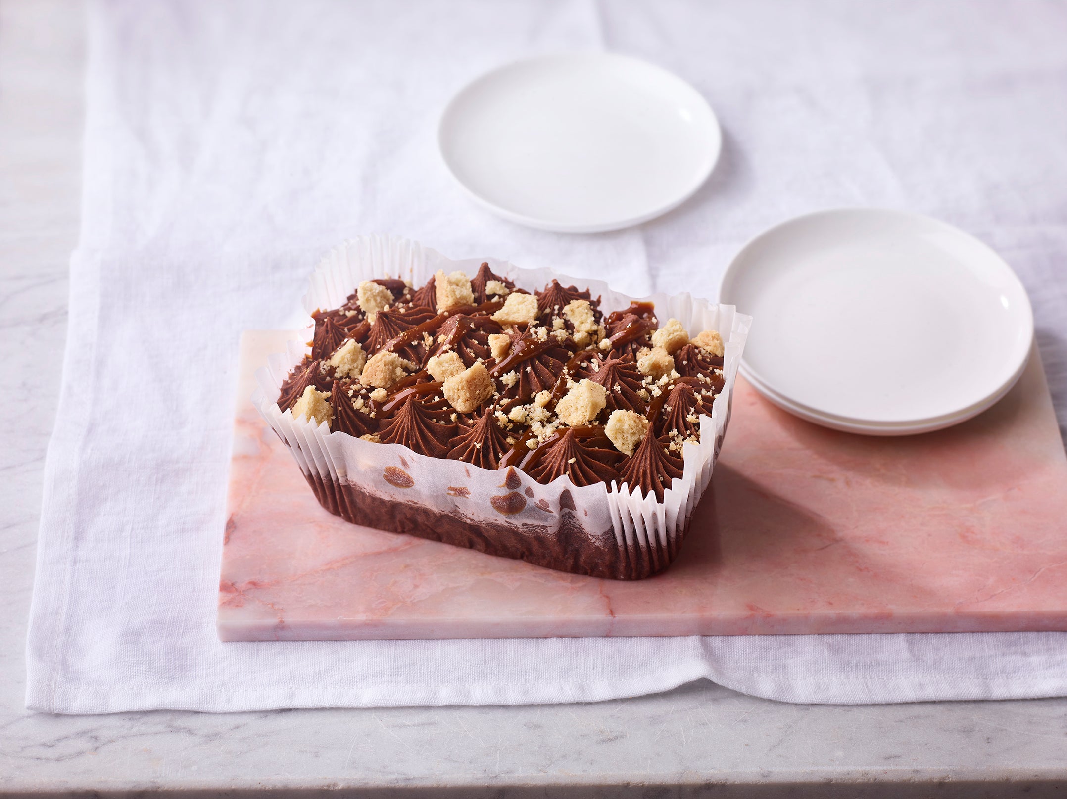 Chocolate loaf cake with crumbly topping on a wooden board with two white plates.