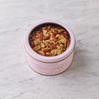Brandy soaked fruitcake with walnuts and almonds in a pink Fiona Cairns tin on a marble surface.