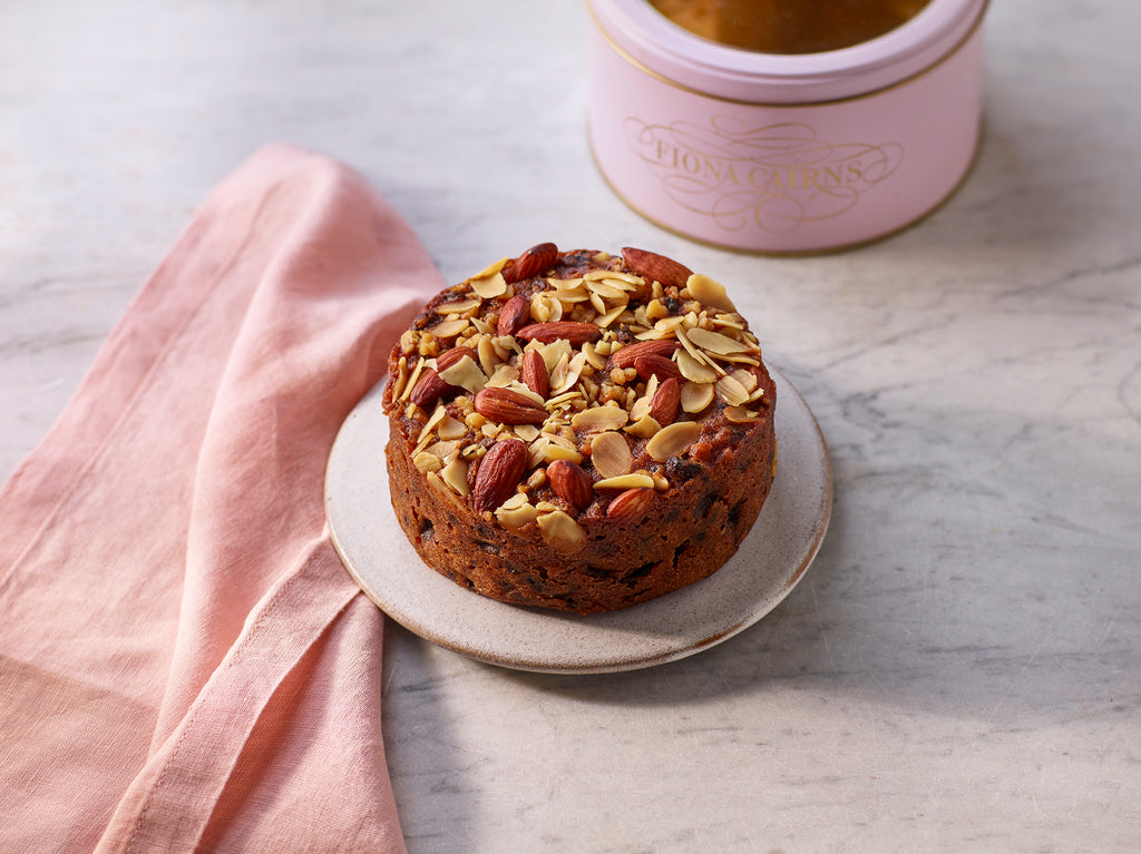 Brandy soaked fruitcake with walnuts and almonds on a plate a marble surface.