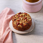 Brandy soaked fruitcake with walnuts and almonds on a plate a marble surface.