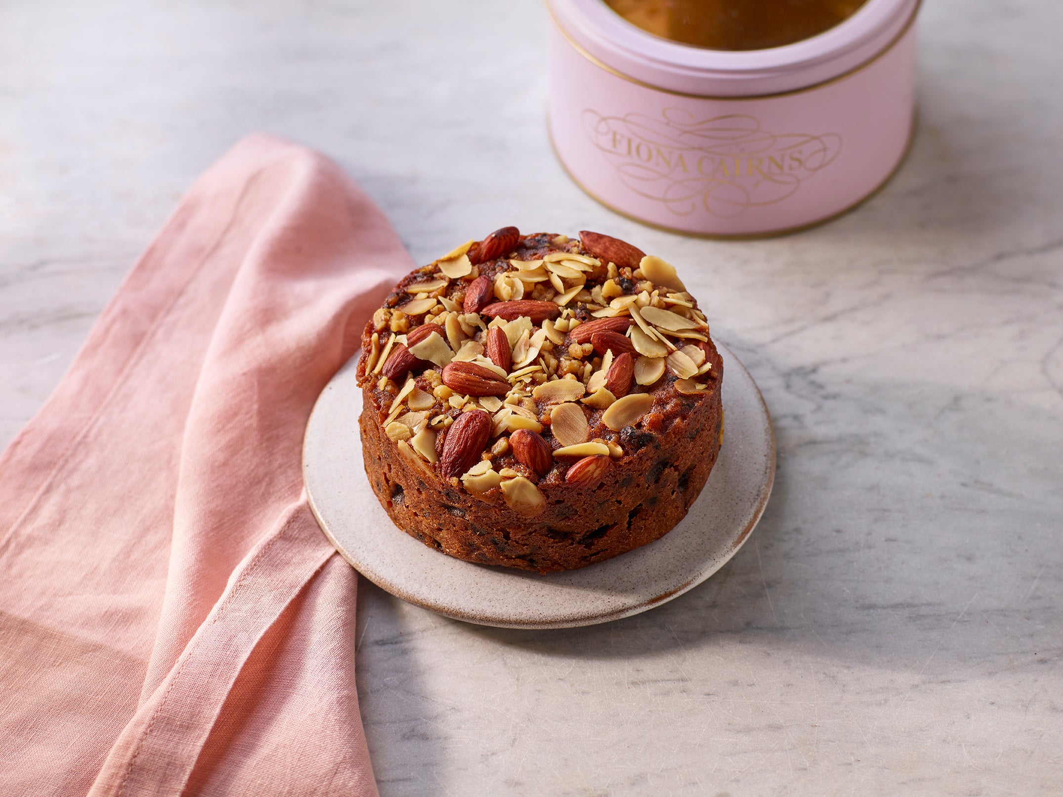Brandy soaked fruitcake with walnuts and almonds on a plate a marble surface.