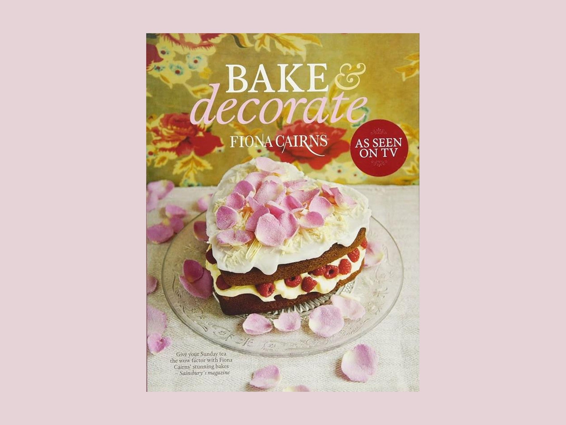 Bake & Decorate by Fiona Cairns book cover featuring a heart-shaped sponge cake with cream, strawberries and rose petals on a pink background.